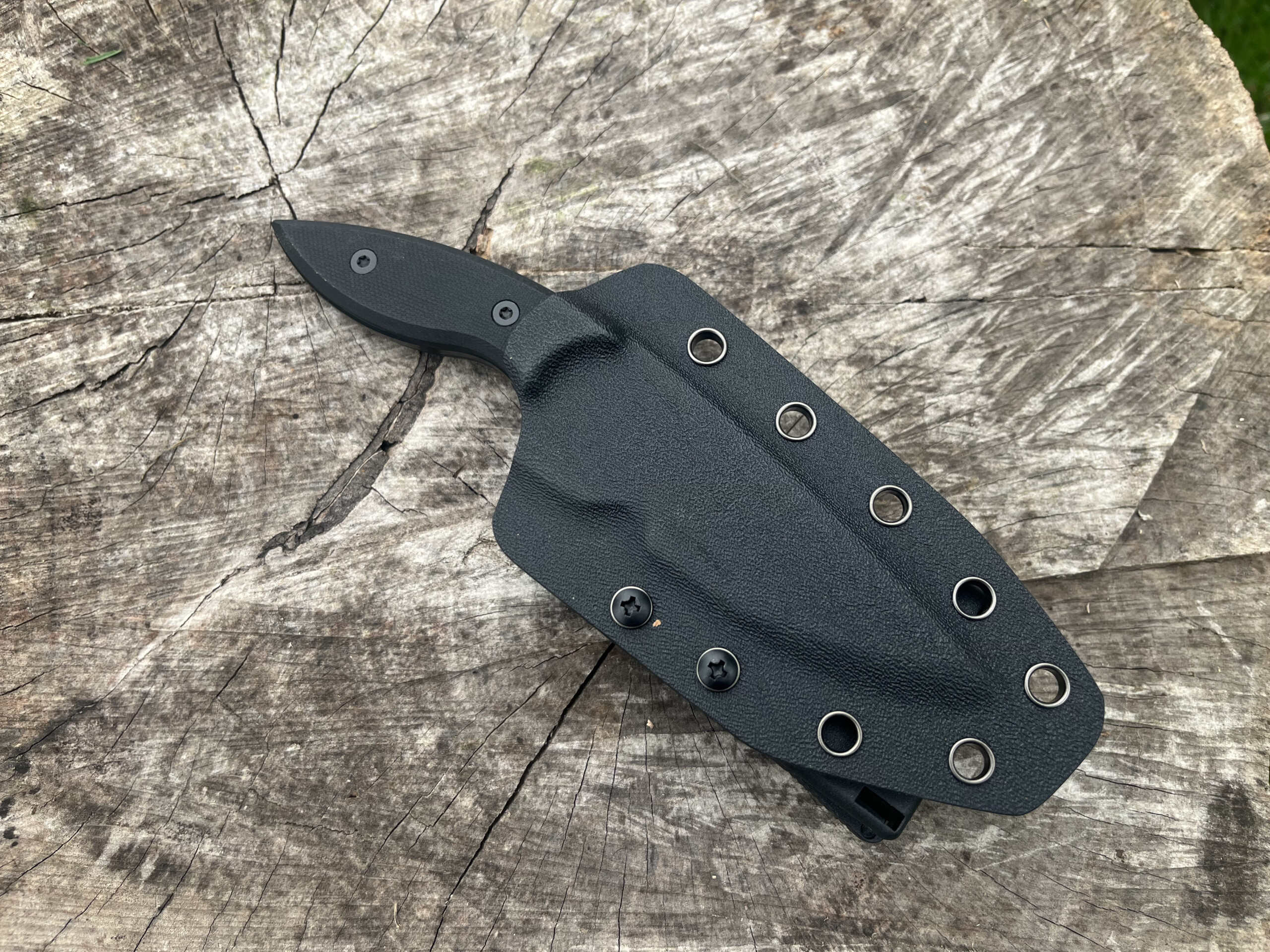 Couteau SHADOW RING rangé dans son étui rigide noir à œillets