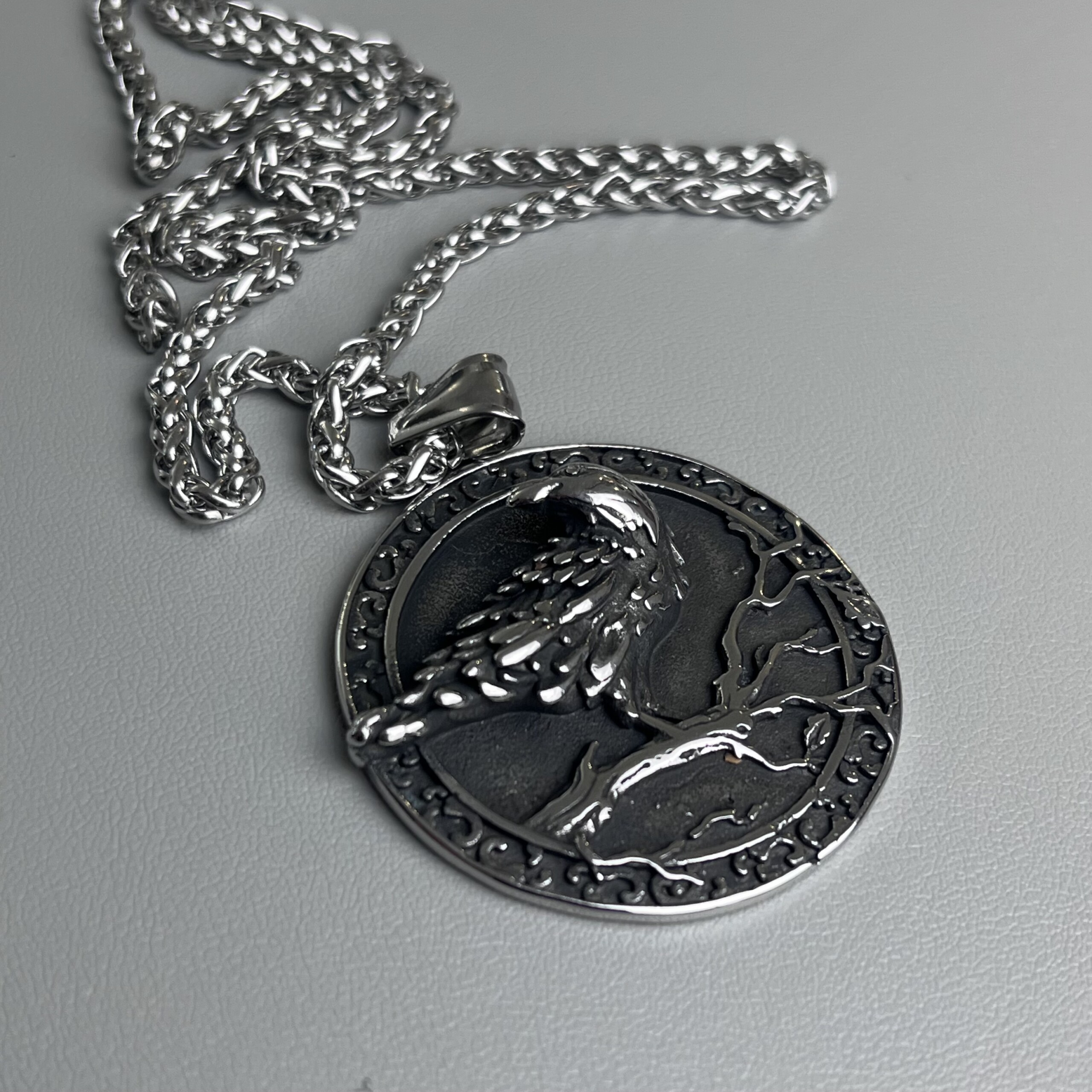 Vue inclinée du pendentif Corbeau d'Odin, détails du plumage en relief et finition acier argenté