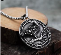 Collier Viking Corbeau d'Odin présenté sur support en bois avec pendentif circulaire argenté